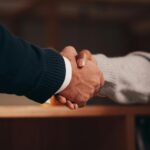 Two hands shaking in a professional setting, symbolizing business deal or agreement.